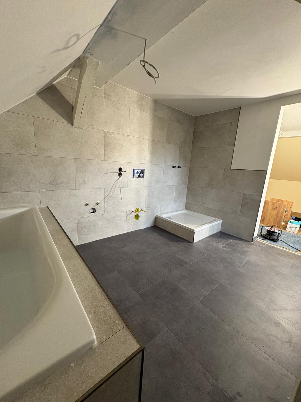 Modernisierter Badbereich mit grauen Wand- und Bodenfliesen