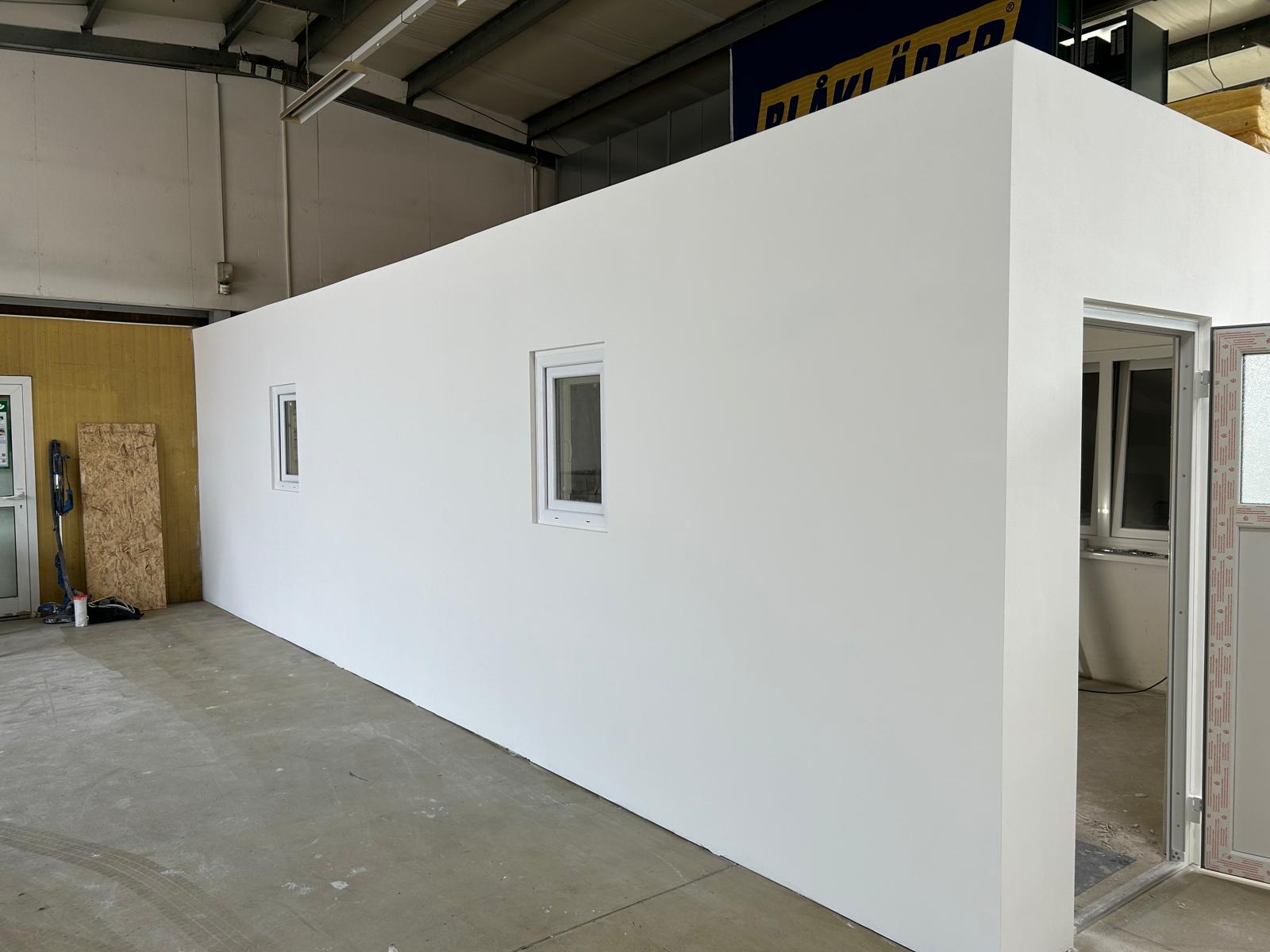 Fertig ausgeführter weißer Trockenbauraum mit zwei Fenstern und Türöffnung